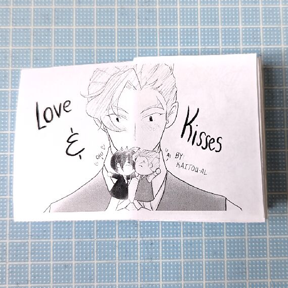 Love & Kisses zine cover with Ainosuke blushing while holding two puppets that look like Tadashi and himself kissing.