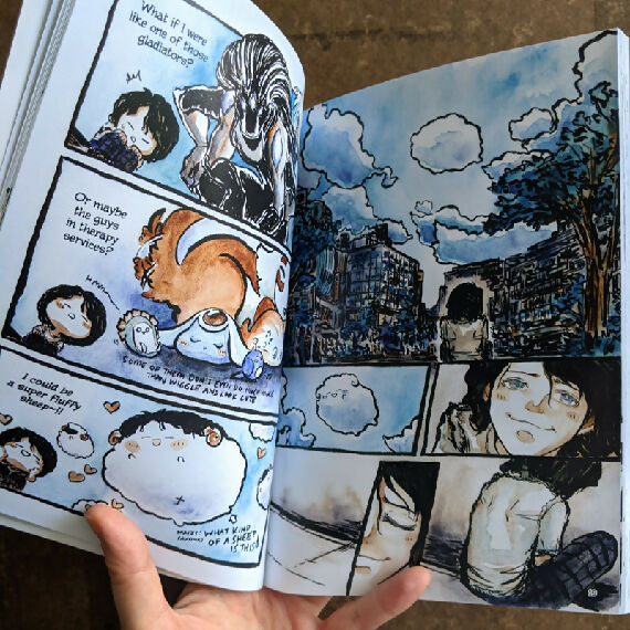 Now Recharging Book 1 opened to a spread showing ink and watercolour comic art of an android daydreaming and pondering different forms they might take, then gazing up to look at the clouds in the sky with a wistful expression.